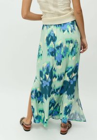 Gonna maxi in tessuto verde chiaro con un motivo floreale astratto blu e verde, dotata di uno spacco laterale e un design fluido.