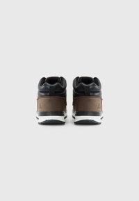 Sneaker marroni e neri con una finitura texturizzata, dotati di una linguetta imbottita, un tirante e una suola bianca con accenti neri.