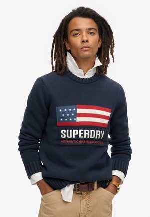 Maglione a maglia blu navy con design della bandiera americana nei colori rosso, bianco e blu, brandizzato "SUPERDRY" e con polsini e bordo a costine.