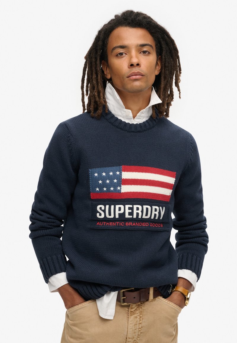 Maglione a maglia blu navy con design della bandiera americana nei colori rosso, bianco e blu, brandizzato "SUPERDRY" e con polsini e bordo a costine.