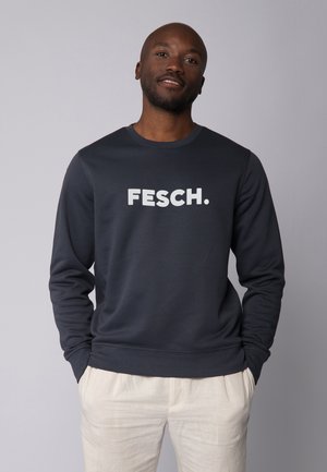 Marineblauwe sweatshirt met lange mouwen en ronde hals, met op de voorkant een grote witte bedrukte tekst "FESCH.". Zachte stofstructuur.