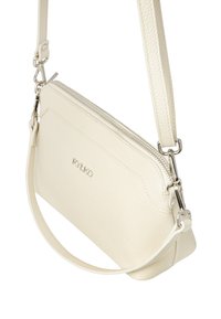 Borsa a tracolla in pelle color crema con cerniera in argento, superficie testurizzata e tracolla regolabile che evidenzia un design elegante e minimalista.