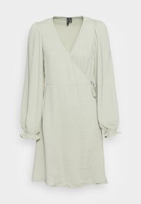 Vestido envolvente verde claro com mangas longas, punhos elásticos e cintura com laço. Com tecido texturizado suave e um decote em v que valoriza a silhueta.