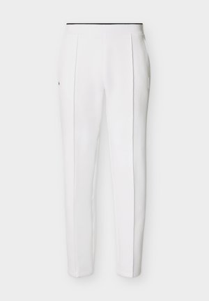 Hvide slim-fit bukser med forreste syninger og sort kantbånd ved taljen, vist på en ensfarvet lys baggrund.