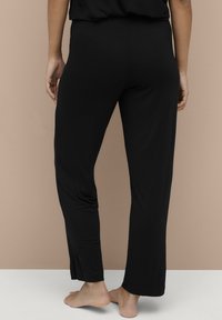 Pantalones negros, ligeros, elásticos, con corte recto, cinturilla elástica y largo hasta los tobillos, con una textura suave y sin patrones visibles.