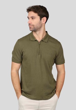 Polo shirt vert olive avec un col zippé, des manches courtes et une texture lisse et douce. Présente un logo discret sur la poitrine gauche.