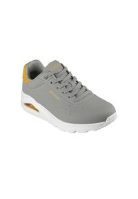 Grijze sneaker met een glad bovenwerk van synthetisch materiaal, vetersluiting en een gele accent aan de hiel. Beschikt over een gecushioneerde witte zool en geperforeerde details.