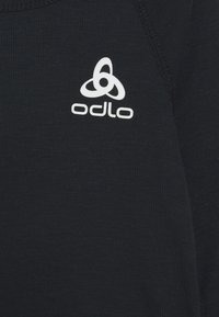 Un tissu noir avec une texture côtelée présente un logo Odlo blanc, affiché de manière proéminente dans le coin supérieur droit.