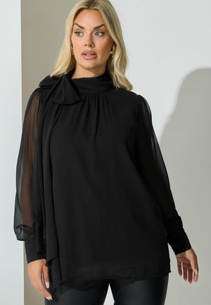 Zwarte blouse met lange doorzichtige mouwen, hoge halslijn, geplooide details en een gestrikte strikaccent. Gemaakt van lichtgewicht, gestructureerde stof.