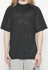 Svart nät T-shirt med kort ärm och rund halsringning, med en Nike Air-logotyp på framsidan och en lös passform för bättre luftgenomströmning.