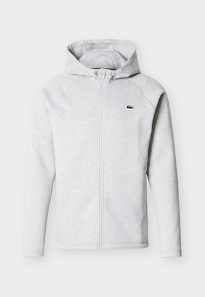 Lichtgrijze hoodie met rits, voorzakken, verstelbare capuchon met trekkoord en een klein groen krokodillenlogo op de linkerborst.