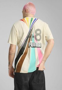 T-shirt in cotone beige con strisce diagonali multicolori in viola, verde, arancione, marrone e rosa. "PUMA" e "48" stampati sul retro.