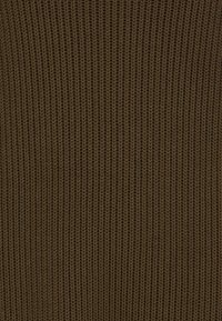 Hnědá pletená tkanina s texturovaným žebrovaným vzorem, který vykazuje rovnoměrně rozložené vertikální stehy po celém povrchu.