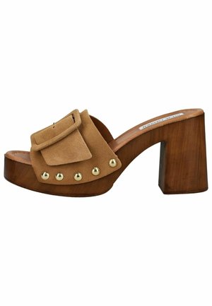 Mule plateforme en suède marron avec talon bloc, clous décoratifs dorés et grande boucle en suède sur semelle en bois.