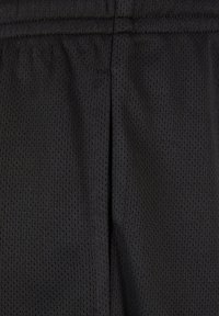 Shorts de sport noirs en tissu mesh léger et respirant, avec une surface texturée présentant un petit motif de trous et une ceinture cousue.
