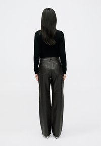 Črne usnjene široke hlače z vidnimi šivi in zadnjimi žepe, oblikovane z visokim pasom in gladko teksturo.