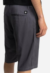 Pantaloni corti grigi con una vestibilità comoda, realizzati in tessuto leggero. Presentano due tasche posteriori e una piccola etichetta con logo sulla tasca destra.