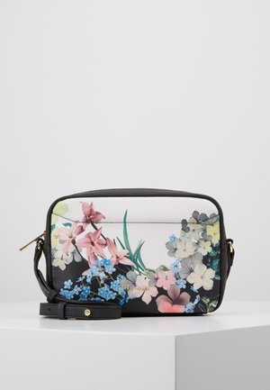 Black and white crossbody bag with colorful floral print and adjustable strap, placed on white surface against gray background.