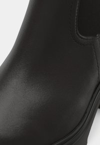 Stivale alla caviglia in pelle nera con finitura liscia, design elegante, punta tonda e pannelli elastici laterali per una facile vestibilità.