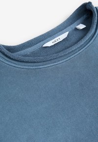 Sudadera de cuello redondo azul hecha de una tela suave con un cuello texturizado y etiqueta blanca en el interior. Sin patrones visibles ni herrajes.