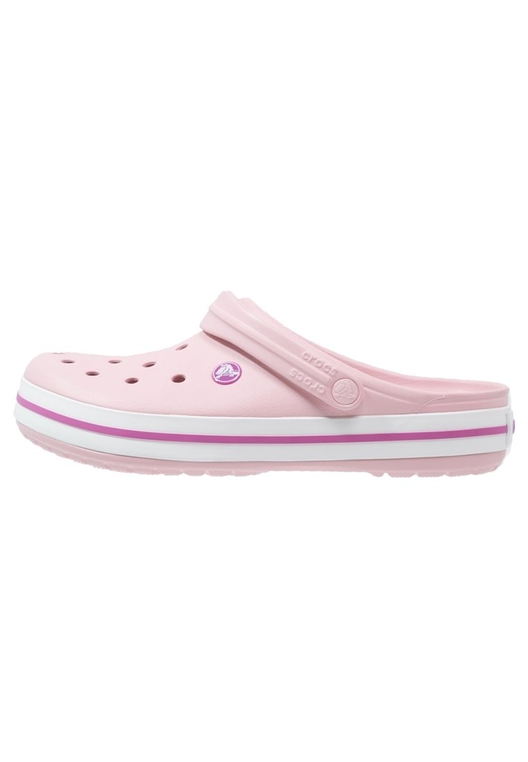 Sabot Crocs rose clair avec des trous de ventilation, semelle à rayures blanches et roses, et bride de talon ajustable.