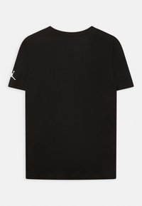 Černé tričko s krátkými rukávy a kulatým výstřihem s malým bílým logem Jumpman na levém rukávu, zobrazené zezadu.