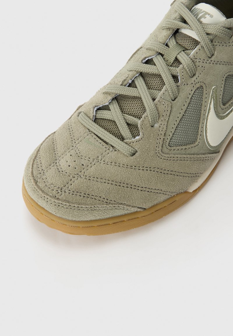 Jasnozielone zamszowe sneakersy z siateczkowymi panelami, teksturowanym czubkiem i gumową podeszwą w kolorze karmelu. Posiadają charakterystyczne logo w kształcie checkmark w białym kolorze.