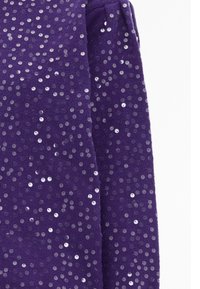 Tessuto viola con una superficie texture coperta di paillettes circolari lucide. Il design ha una forma aderente con polsini elasticizzati.