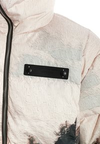 Chaqueta acolchada rosa claro con tejido texturizado, que presenta una franja horizontal gris y una etiqueta negra con botones en la zona del pecho.