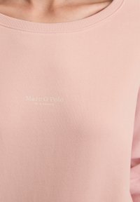 Lichtroze sweatshirt met een geribbelde ronde hals en zachte textuur. Heeft een geprint logo in een contrasterende kleur.