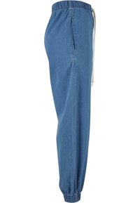 Pantalones jogger de mezclilla azul con cintura elástica y cordón, bolsillos laterales y puños fruncidos en los tobillos. Tejido suave y ligero.