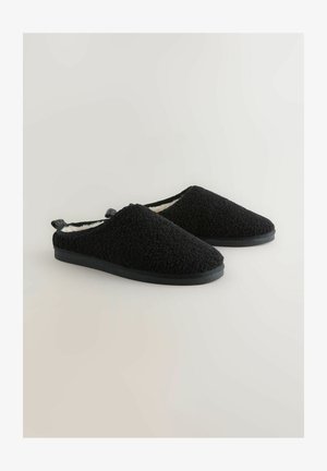 Černé nazouvací pantofle vyrobené z měkké texturované tkaniny s huňatým interiérem. Mají plochou černou podrážku a ucho na patě pro snadné obouvání.