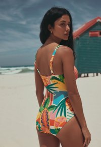 Bunter Einteiler-Badeanzug mit tropischen Mustern aus Blättern und Früchten. Material wirkt glatt mit verstellbaren Trägern. Rückansicht.