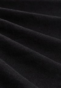 Primer plano de una suave tela negra con pliegues diagonales y una textura lisa.