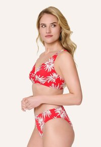 Bikini rojo con estampado floral blanco, que presenta un diseño frontal retorcido en la parte superior y un bikini de tiro alto a juego. Textura de tela suave.