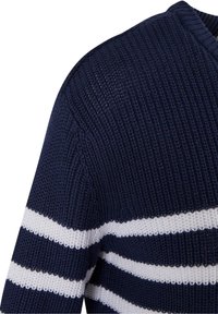 Manche de pull en maille bleu marine avec des rayures horizontales blanches épaisses alternées et une texture côtelée.