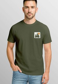 Olivgrünes Baumwoll-T-Shirt mit einem weißen Grafikdesign von zwei immergrünen Bäumen und einer Sonne im linken Brustbereich. Kurzärmlig.