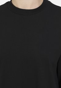 Svart crewneck sweatshirt tillverkad av texturerad bomull. Inkluderar en ribbad halsringning, med slät tyg och normal passform. Inga mönster eller accenter.