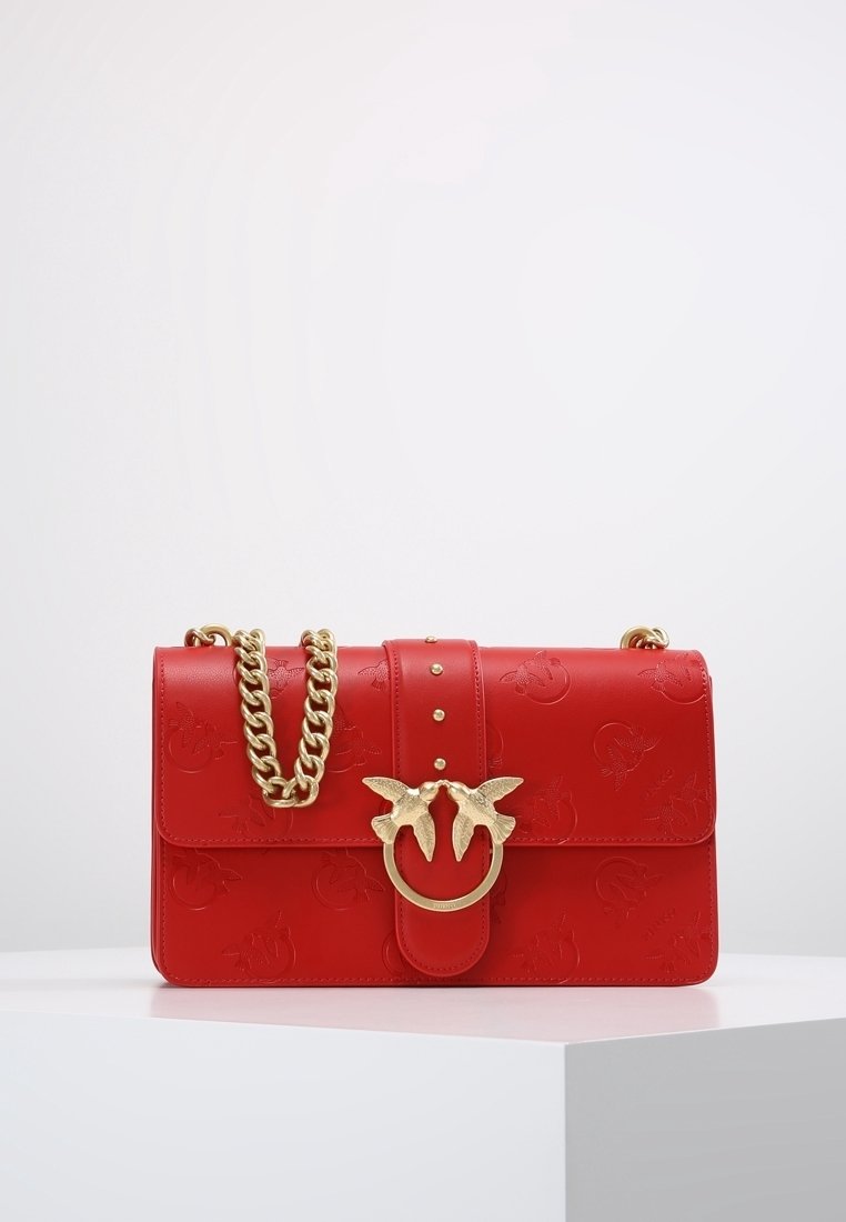 Borsa a tracolla in pelle rossa con motivi in rilievo, hardware dorato, catena e un distintivo motivo di uccello sul blocco.