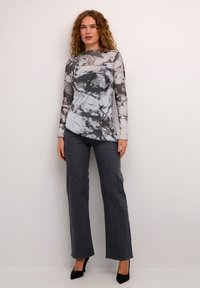 Långärmad topp i svart och vit marmor mönster, scallopad halsringning, matchad med grå jeans med nitar. Svarta klackar.