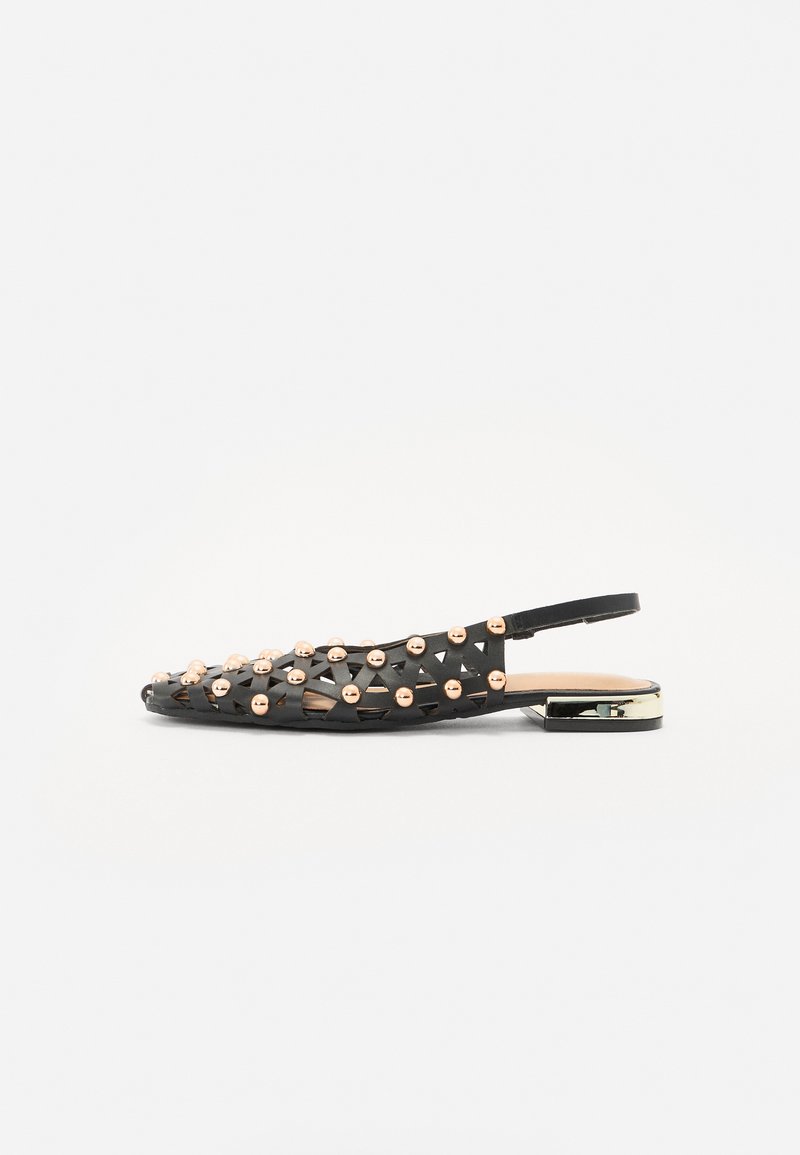 Scarpa slingback nera con design intrecciato, decorata con borchie metalliche, tacco flat e un accento dorato lucido sul tacco.