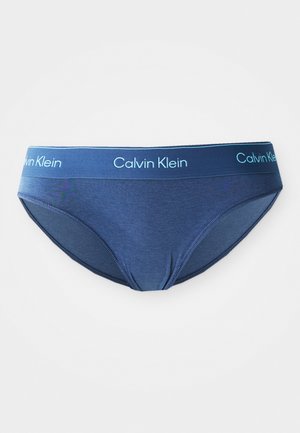 Kratke gaće od tamnoplave pamučne mješavine sširim tamnoplavim elastičnim pojasom na kojem je prikazan bijeli "Calvin Klein" logo. Glatka tekstura i klasičan dizajn.
