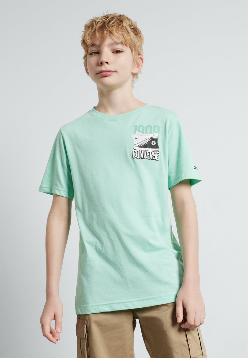 Mintgrønn bomull T-skjorte med rund hals, korte ermer, og et trykt svart-hvitt Converse-design på brystet.