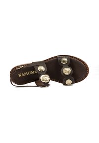 Sandalia deslizante de cuero marrón con tres botones decorativos metálicos, borde cosido y marca en dorado "KAMOME" en la plantilla.