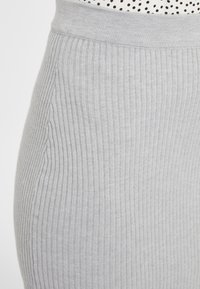 Grauer, gerippter Rock mit einem dicken, elastischen Taillenbund. Der Stoff hat eine weiche Textur und vertikale Streifen, die entlang der Länge verlaufen.