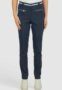 Pantalons ajustés bleu marine avec une texture lisse, dotés de poches zippées et d'accents rayés blancs sur la taille.