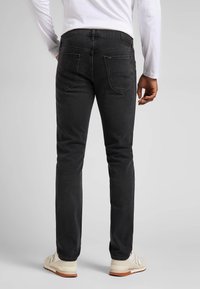 Svarta slim-fit jeans med medelhög midja, med en slät yta, två bakfickor och en logotyp på midjebandet.