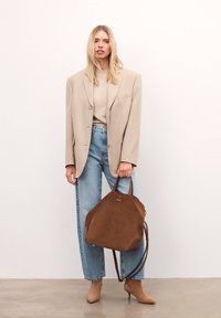 Beežikas üle suuruslik bleiser, heledast kangast kampsun, kõrge vöökohaga sinised teksad, pruun seemisnahast kott nahast detailidega ja beežid terava ninaga kontsakingad.