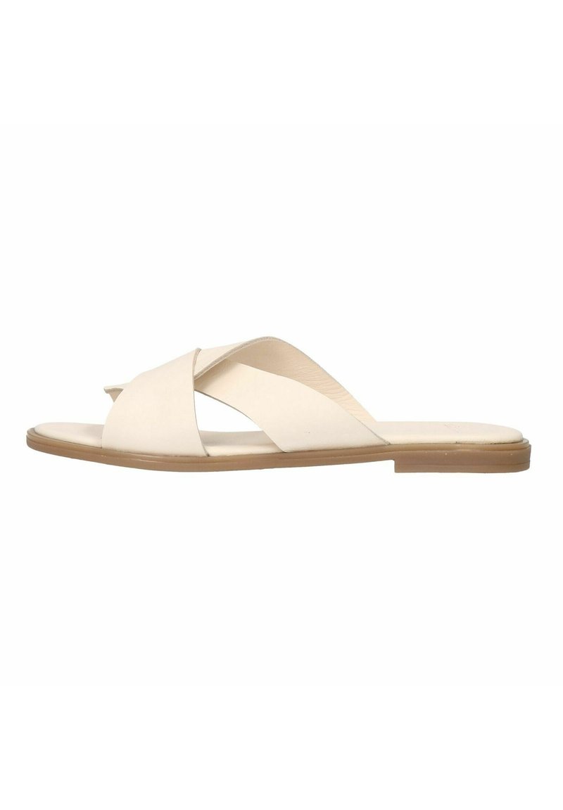 Beige leather slide sandals with cross-strap design, flat sole, and minimalistic profile. Smooth texture and light color for versatility.