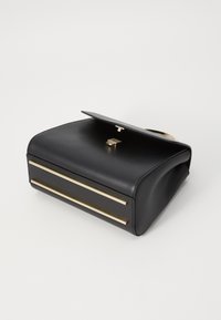 Borsa a tracolla in pelle nera con una texture liscia, caratterizzata da dettagli in metallo dorato e una striscia orizzontale alla base. Chiusura a patta.